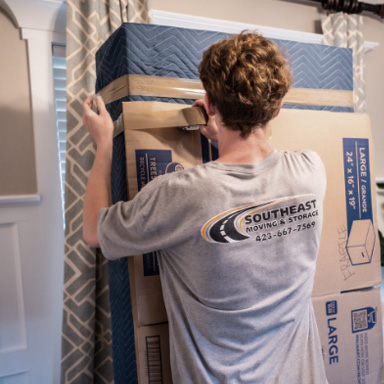 mover tapes a mattress to boxes for moving.