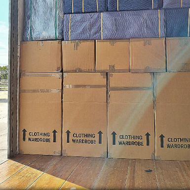 cardboard boxes labeled clothing wardrobe are stacked in a truck