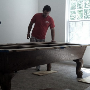 man in red shirt assembling a pool table.